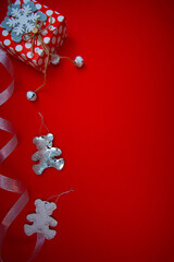 Vertical shot of a red gift box and Christmas ornaments with copy space isolated on red background