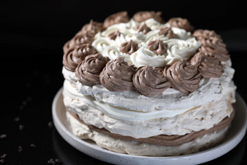 Meringue cake with nuts and black and white chocolate cream.