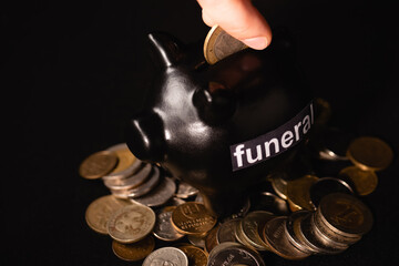 cropped view of man putting coin in piggy bank on black , funeral concept