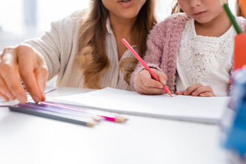 cropped view of girl drawing pictures with colorful pencils while visiting psychologist