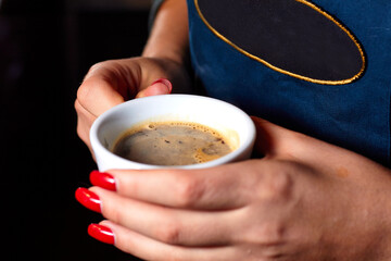 Female hands with coffee drink. Barista in an apron