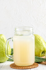 Delicious guava fruit with fresh juice set on white wooden table background.
