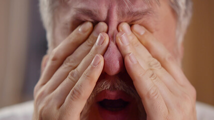 Close up portrait of grey haired senior man rubbing eyes feeling fatigue