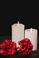 red carnation flowers and candles on black , funeral concept