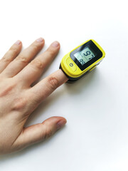 Human hand with a pulse oximeter on the index finger on a white background
