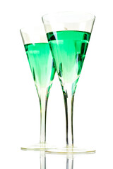 Champaign glasses filled with clear green liquid. Cocktail. Studio photo isolated on white background. Reflective surface. 