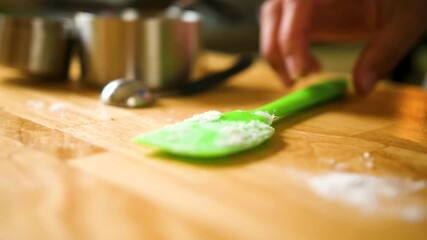 close up person picking up and putting down bright green spatula for baking