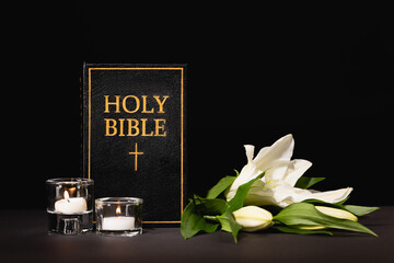 lily, candles and holy bible on black , funeral concept