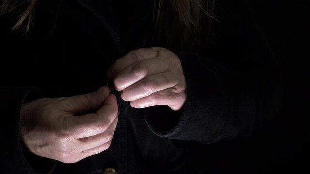 Woman buttoning up a black velvet coat medium shot