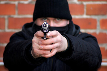 Maskierter Mann mit Schusswaffe in den Händen