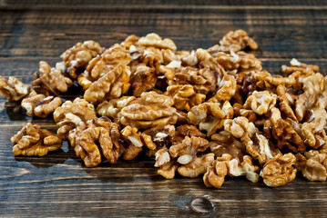 Walnut texture close up. Many halves of peeled nuts on an old wooden board. Food on a background of shabby brown board.