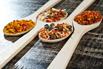 A mixture of various spices in a wooden spoon. Spices and seasonings on an old shabby board. Mix on a pile close up.
