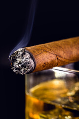 detail of lit cigar, giving off smoke.