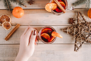 Woman holds cup of hot mulled wine in her hands. Winter warming drink for the holiday.