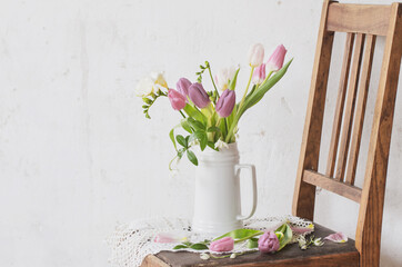 spring flowers on old chair on background old white wall