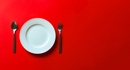Obraz na płótnie Canvas Empty white plate on red background. 赤背景上にある空っぽの白いお皿。
