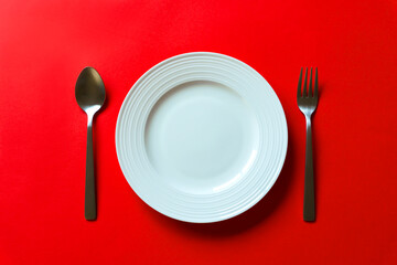 Empty white plate on red background.  赤背景上にある空っぽの白いお皿。