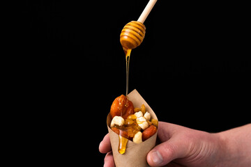 Liquid honey flows down on dried fruits.