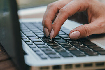 Hands writing ond a keyboard of a laptop or a notebook in Home Office