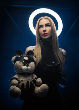 a woman with a halo in black clothes with a tattoo machine and a toy bear