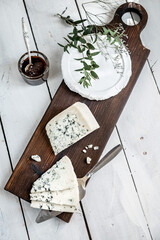 a piece of dor blue cheese on a cheese board with knives. delicacy blue cheeses. Homemade cheese making. top view