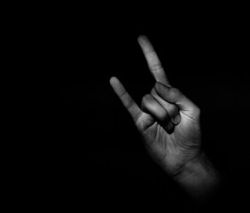 Goat hand gesture sign, arm symbol on a dark background with a light accent light