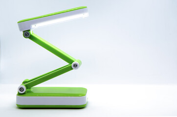 Compact foldable portable LED Desk Lamp with flexible body made of bright green plastic on a white...