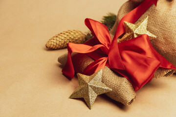 The gift is wrapped in a cloth from a bag tied with a red ribbon and a decorative bag on a beige background.