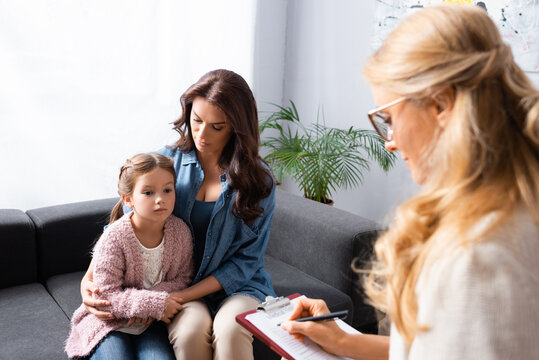 worried mother hugging daughter while visiting psychologist, stock image
