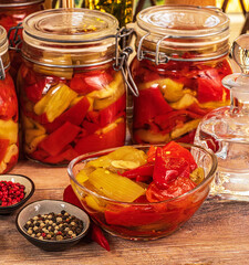 
Eggplant and red pepper snack in glass jars with spices and olive oil on the table.