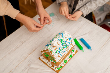 The boy makes a gingerbread house. Preparing for the holiday, creative activity.