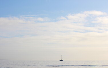 A photograph of a yacht on the horizon with big sky and ocean. Calm, mindfulness concept