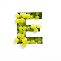 Letter E of English alphabet of green grape and cut paper isolated on white. Typeface made of fresh berries