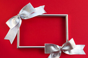 Bright festive background. empty frame and silver bows on a red background. conceptual greetings for Christmas, Thanksgiving, New Year, Mother's Day, Birthday, Valentine's Day. Flat lay, copy space