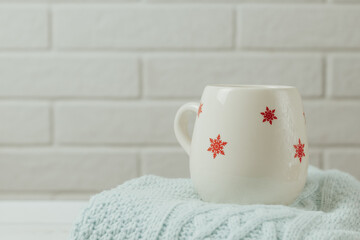 Winter atmosphere.Cup with red snowflakes of tea, cacao or coffee on warm sweater. Scandinavian concept.