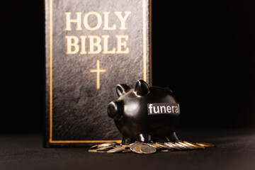 piggy bank with coins and holy bible on black , funeral concept