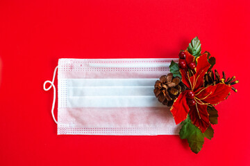 New year's holiday background. Medical mask and Christmas decoration on a red background. The concept of Christmas in the context of the coronavirus pandemic. Flat lay. Greeting card for Christmas.