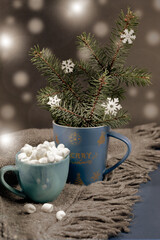 Obraz na płótnie Canvas Xmas mug with fir branches, cup of coffee or cocoa with marshmallows on grey plaid on dark. Cozy hugge atmosphere.