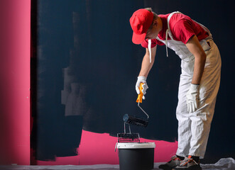 Male decorator painting a wall with black color.