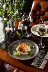 grilled salmon steak with mashed potato and glass of white wine on wooden table at restaurant