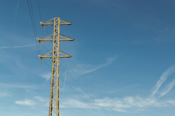 High voltage electrical transmission tower, blue sky and clouds.