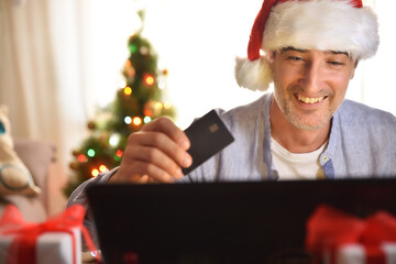 Concept man buying christmas gifts online at home with card