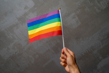 Person hand holding and waving an LGBT pride flag. Multicolored peace flag movement. Original color symbol of gay pride. Rainbow flag on white background