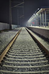 Aufnahme einer leeren Gleisanlage in den Nachtstunden auf einem hell beleuchteten Bahnsteig