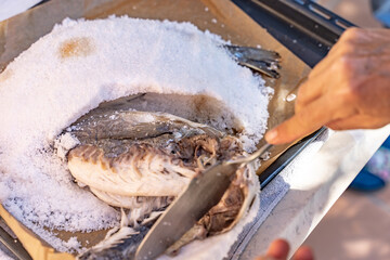 Closeup of gilt head bream wrapped in salt on aluminum foil. Spanish tapas and pinchos outdoor...