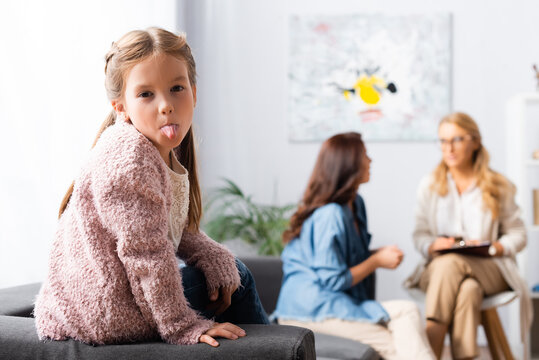 daughter fooling around while mother talking to psychologist, stock image