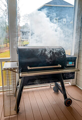 A bbq smoker on a porch giving off smoke - 395779326