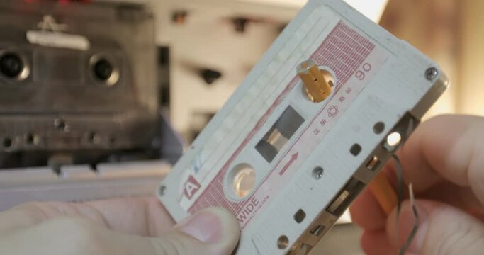 Manually rewind a cassette tape with a pencil. Male hands insert a retro cassette into a tape recorder.