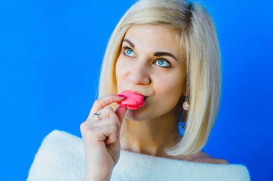 Photo of charming woman in basic clothing eating two macaron biscuits isolated over pink background