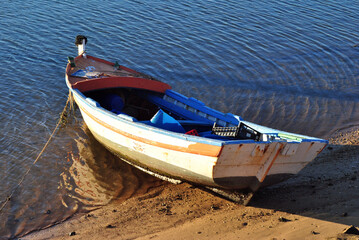 Naklejka na ściany i meble Empty Wooden Fishing Boat Moored beside Sandy Beach 